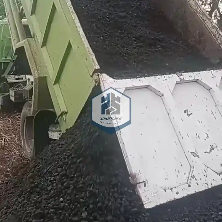 Truk logistik sedang melakukan bongkar muat batu base course di Depok