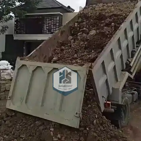 Pekerja mengawasi proses bongkar muat batu base course di Tangerang