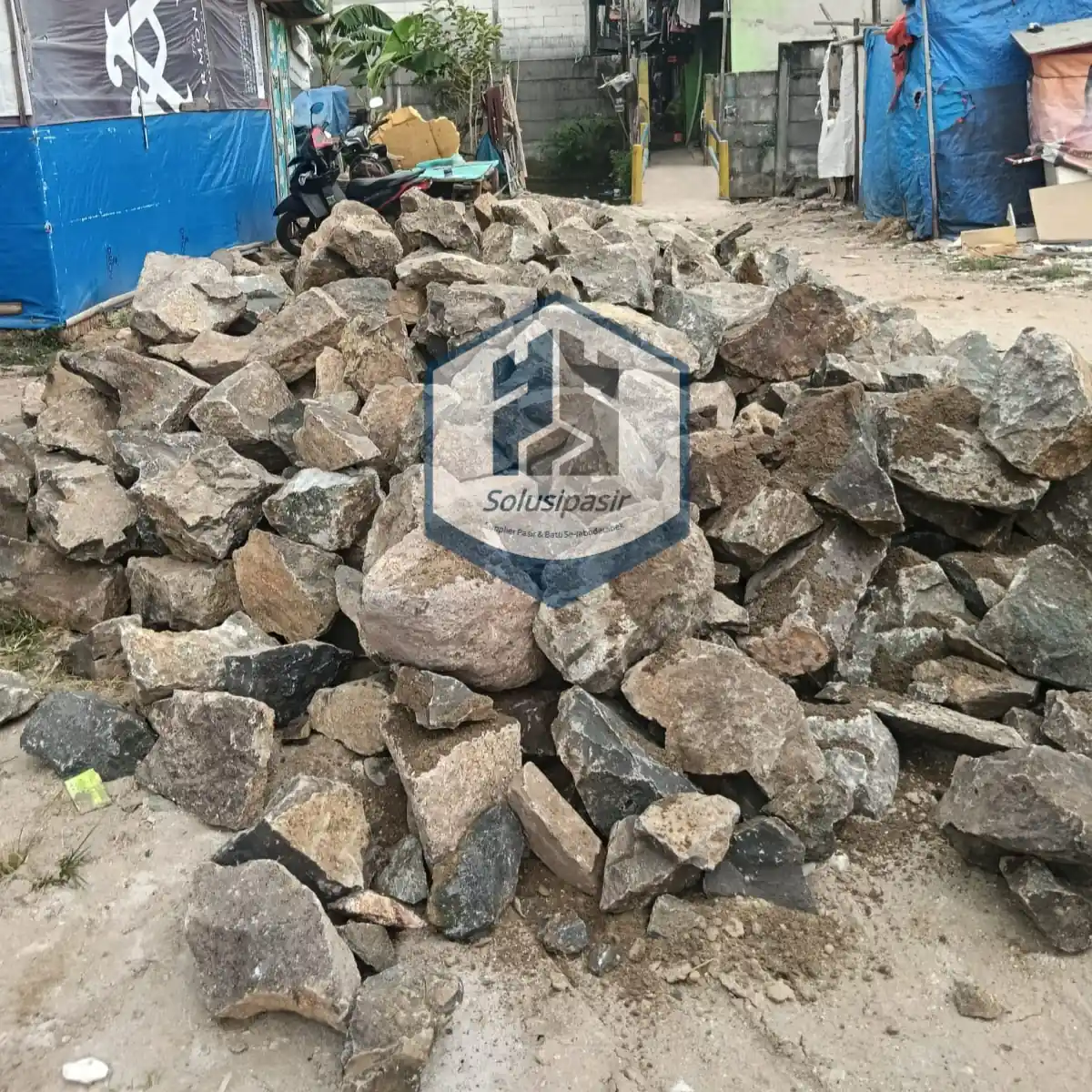 Proses bongkar muat batu belah pondasi untuk proyek konstruksi di Bekasi