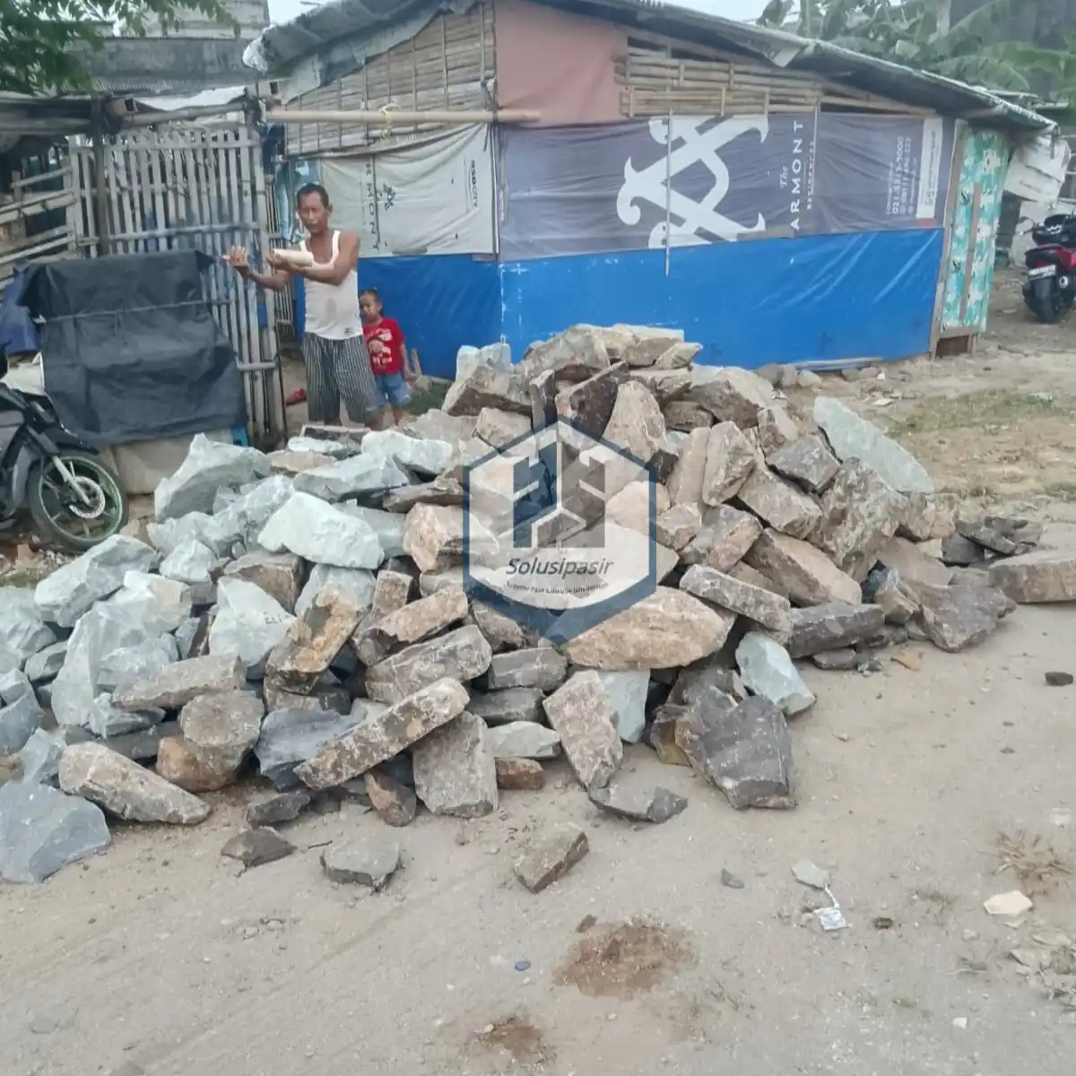 Truk logistik sedang melakukan bongkar muat batu belah pondasi di Depok